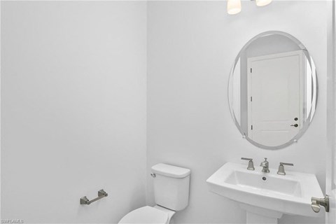 a white bathroom with a mirror and a toilet and a sink