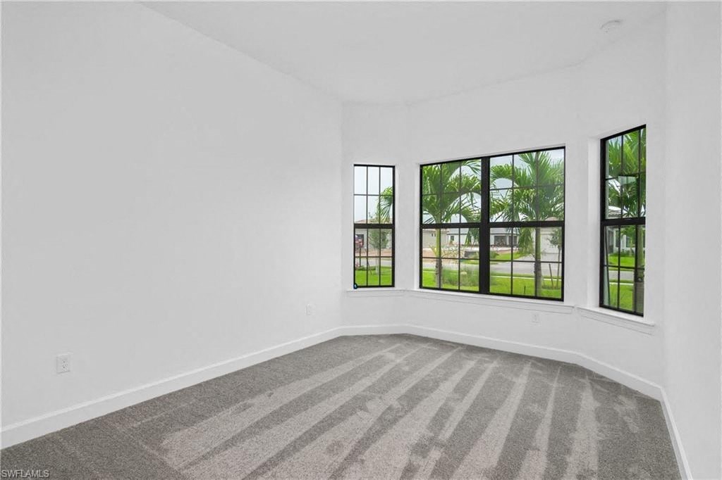an empty living room with large windows and carpet