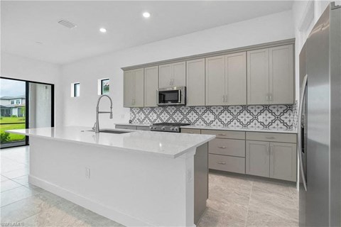 a white kitchen with a large island and stainless steel appliances