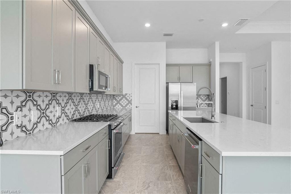 a large white kitchen with white counter tops and stainless steel appliances