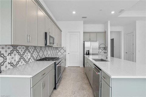 a large white kitchen with white counter tops and stainless steel appliances