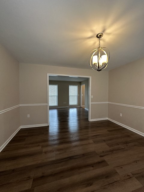 an empty living room with wooden floors and a chandelier