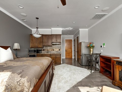 a bedroom with a bed and a kitchen in the background