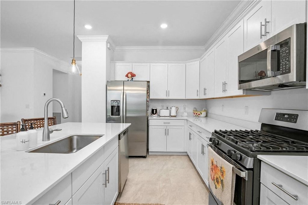 a white kitchen with stainless steel appliances and a sink