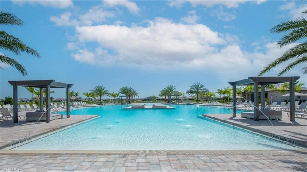 a large swimming pool with chairs and palm trees