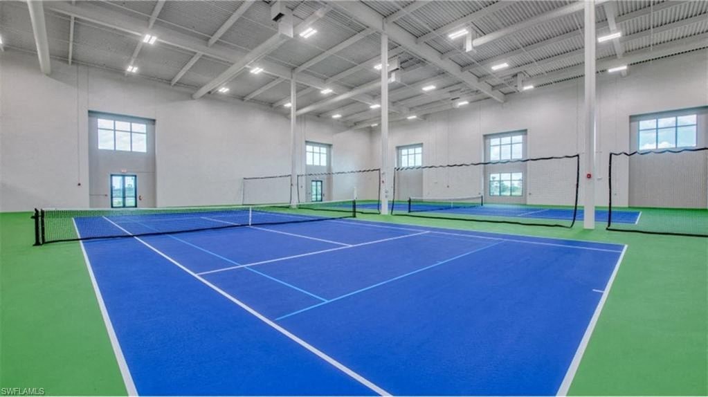 an indoor tennis court in a large room with windows