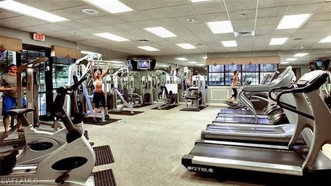 a gym with a lot of exercise equipment and people in it