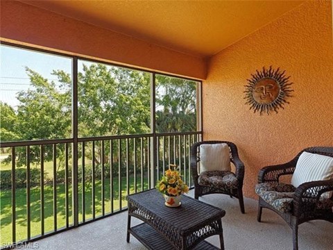 a balcony with chairs and a table and a window