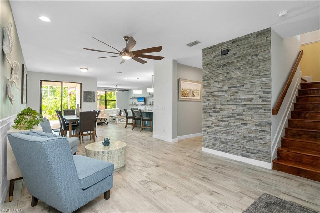 a living room and dining room with a staircase and a stone fireplace