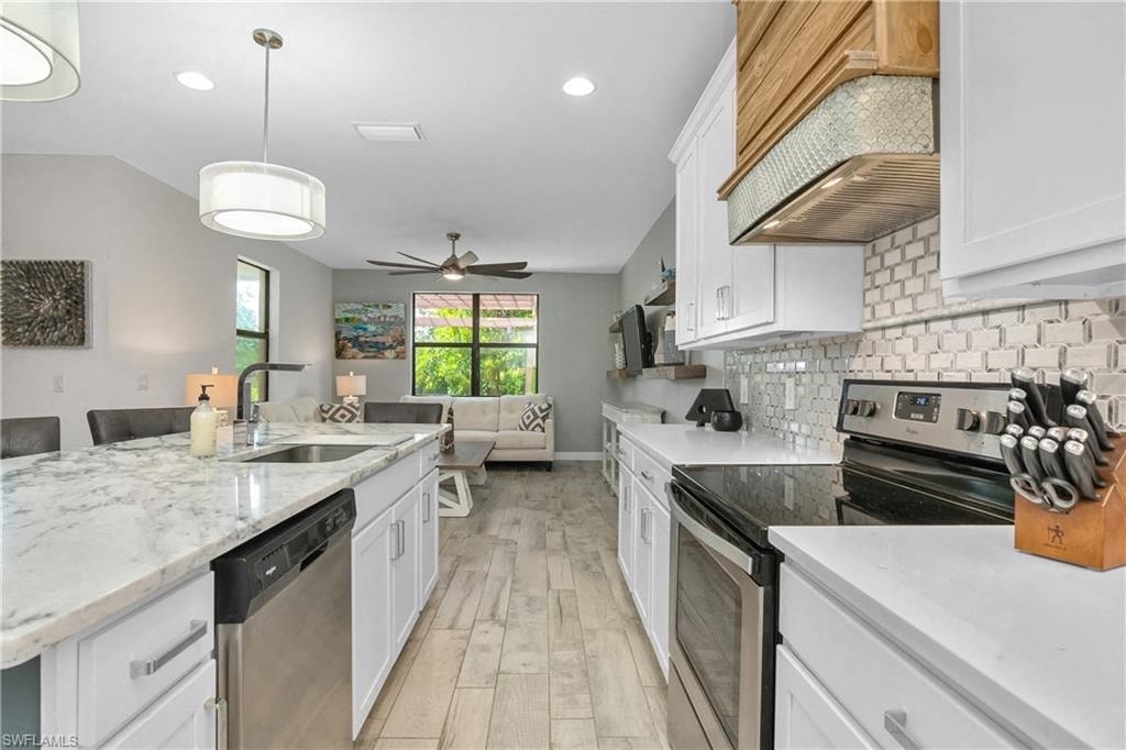 a large kitchen with white cabinets and black appliances