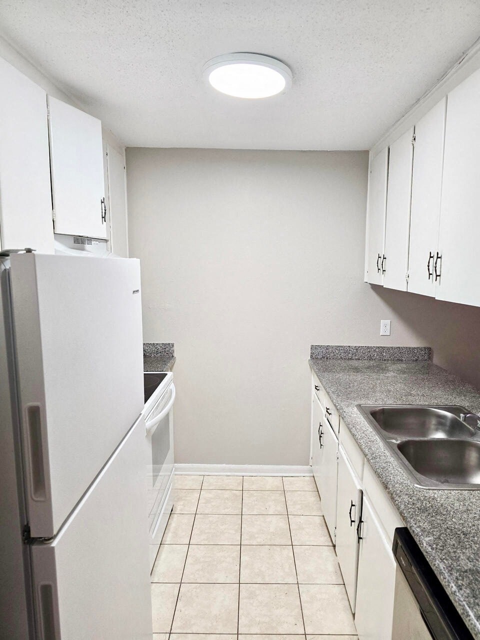 a kitchen with white cabinets and a sink and a refrigerator