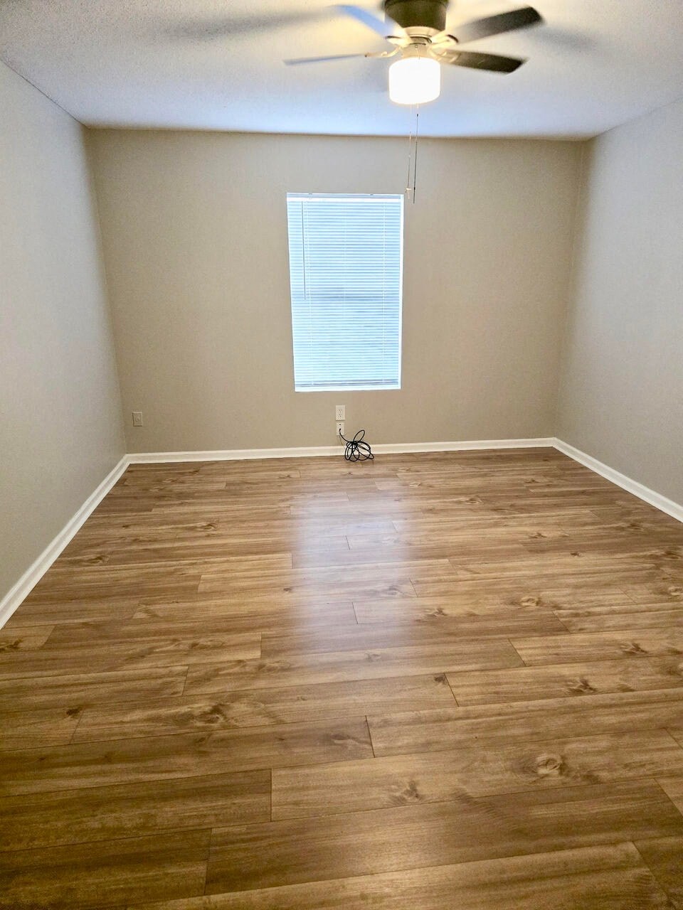an empty room with wooden floors and a ceiling fan