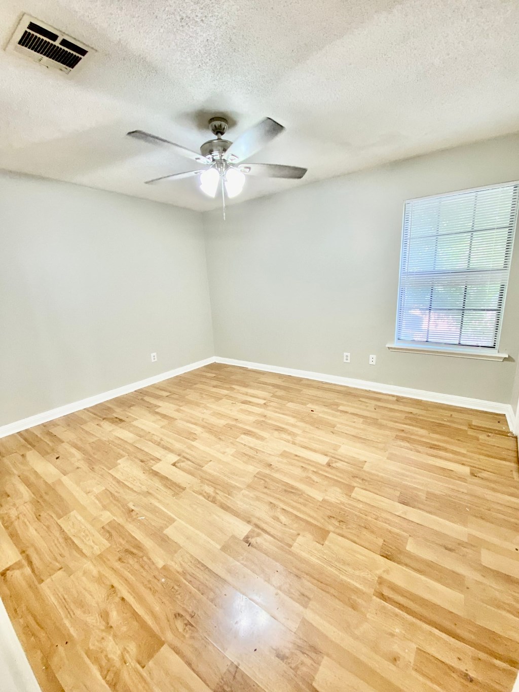 A room with a ceiling fan and wooden flooring.