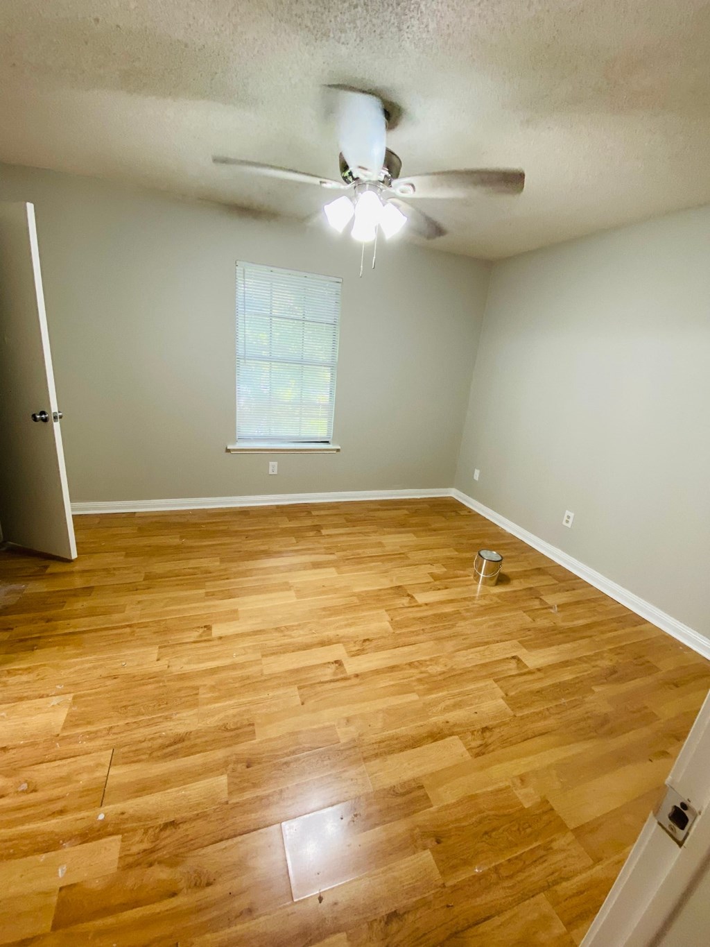 A room with a ceiling fan and wooden flooring.