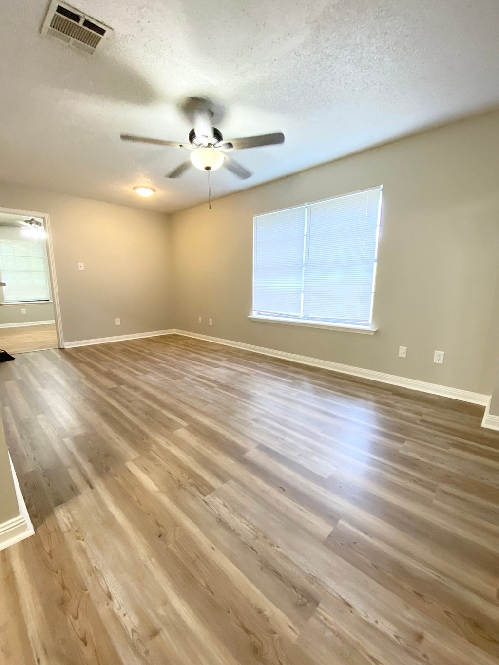 A room with a ceiling fan and wooden flooring.