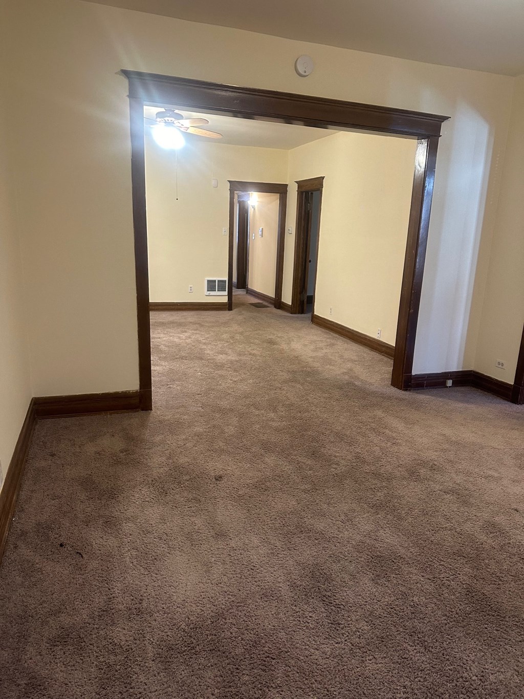 an empty living room with a carpeted floor and several doors