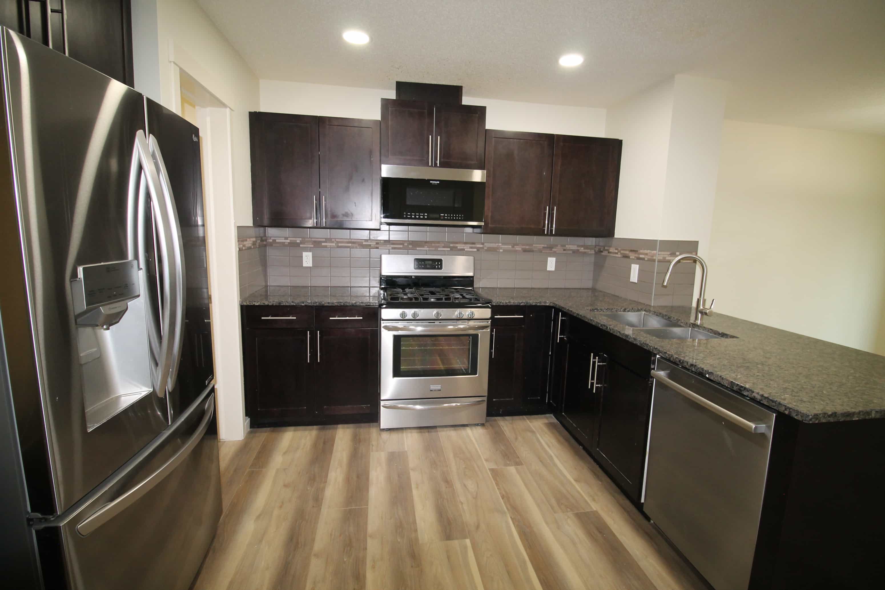 a kitchen with stainless steel appliances and wooden floors