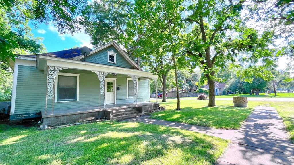 a blue house with trees and a sidewalk