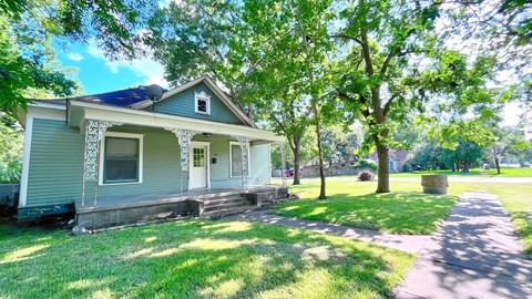 a blue house with trees and a sidewalk