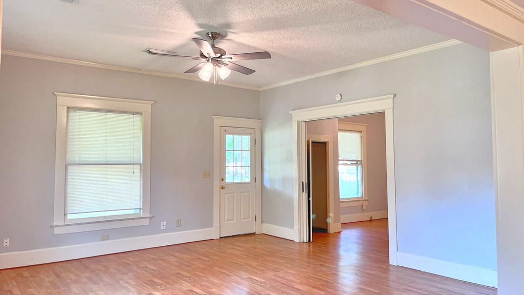 an empty living room with a ceiling fan