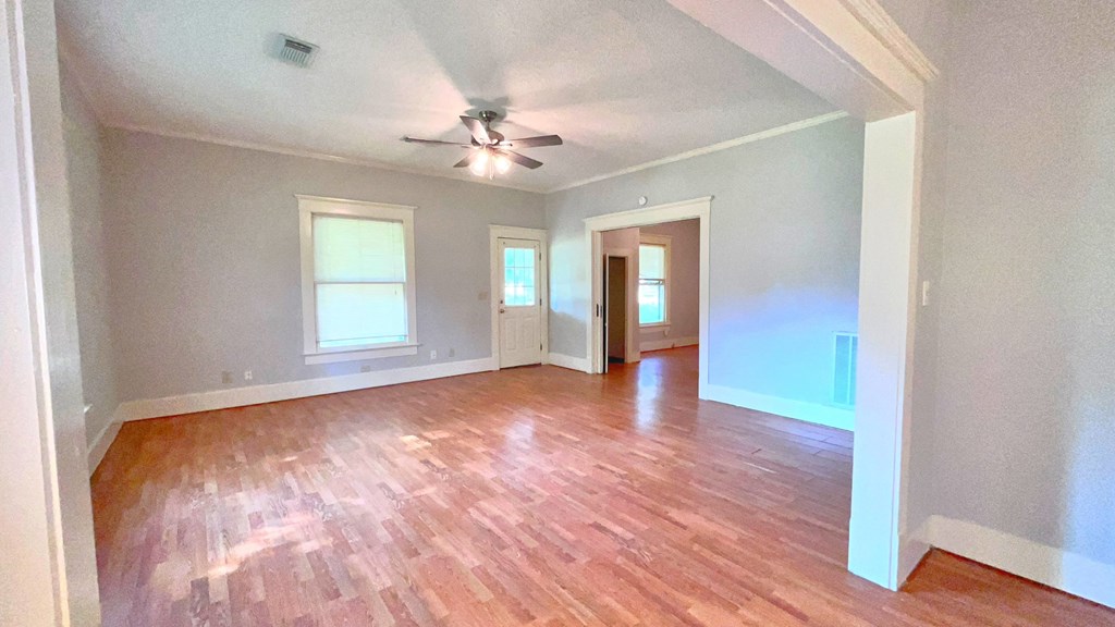 an empty living room with a ceiling fan and wood floors
