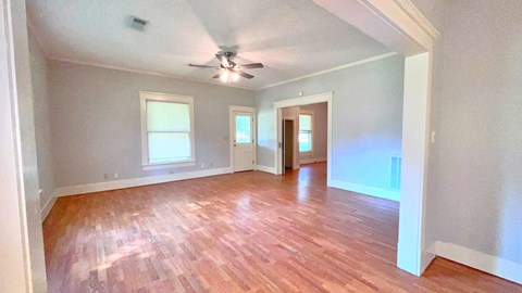 an empty living room with a ceiling fan and wood floors