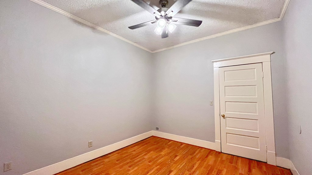 an empty room with wood floors and a ceiling fan