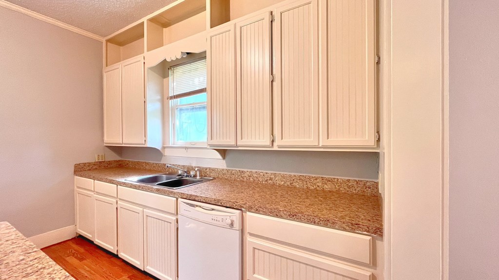 a kitchen with white cabinets and granite counter top and a sink