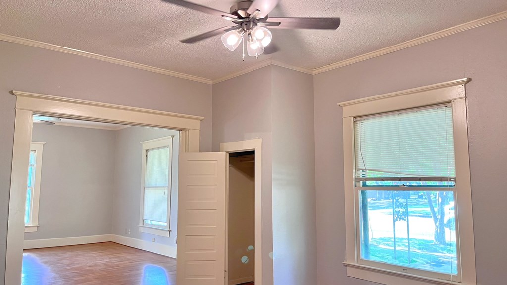 an empty living room with a ceiling fan and a window