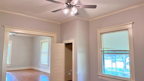 an empty living room with a ceiling fan and a window