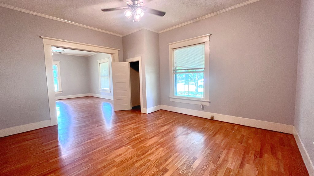an empty living room with wood floors and a ceiling fan