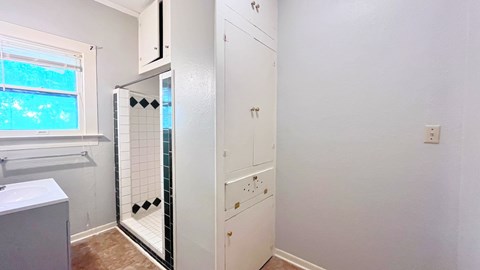 a bathroom with white cabinets and a shower and a sink