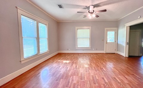 an empty living room with wood floors and a ceiling fan