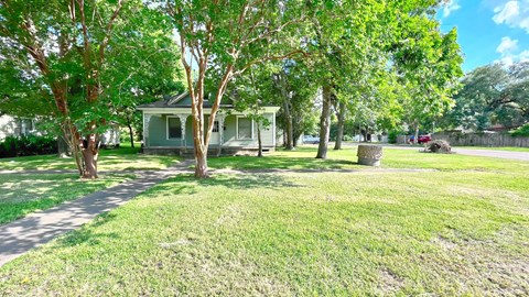 a small green house with trees in front of it