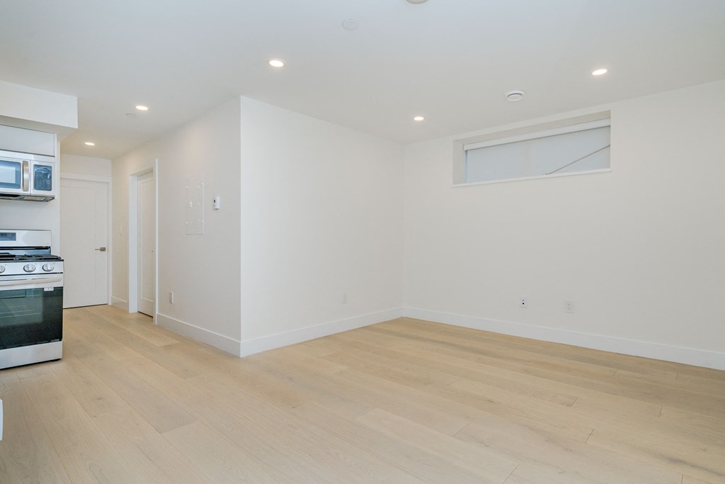 a kitchen and living room with white walls and wood flooring