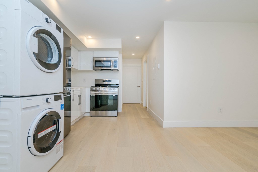 a washer and dryer in a laundry room with a wood floor and white