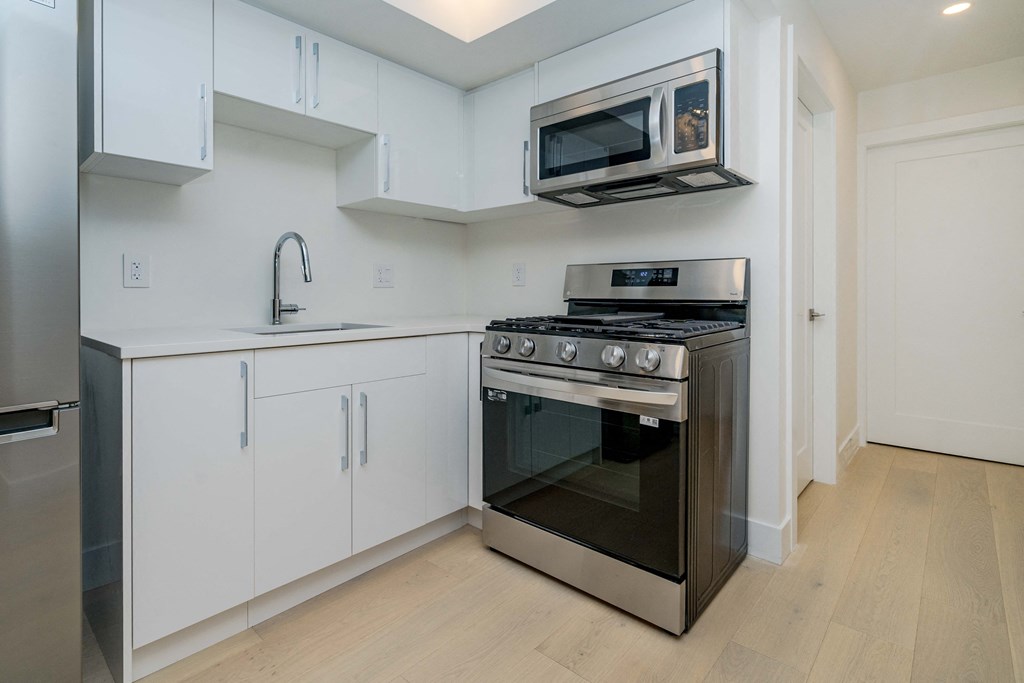 a kitchen with white cabinets and stainless steel appliances and a microwave