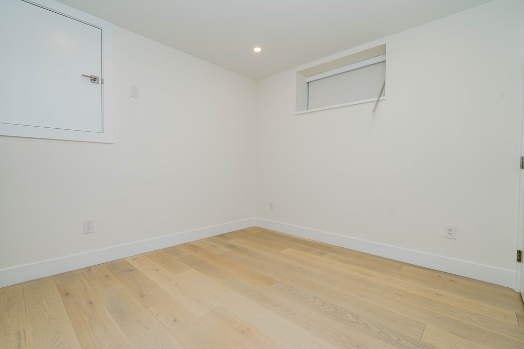 a bedroom with white walls and wood flooring and a window