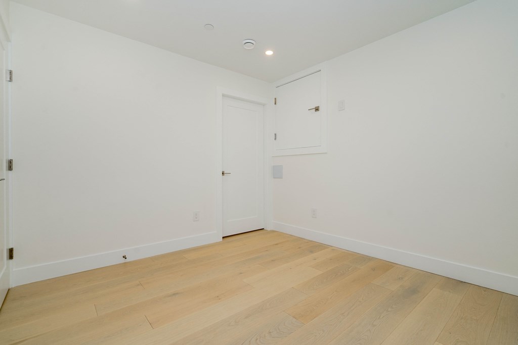 a bedroom with white walls and wood floors