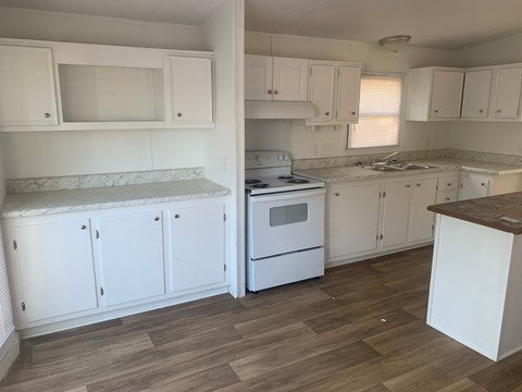 A kitchen with white cabinets and a wood floor.