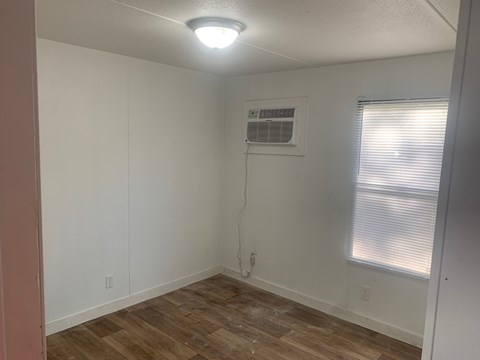 A room with a window and a wall-mounted air conditioner unit.