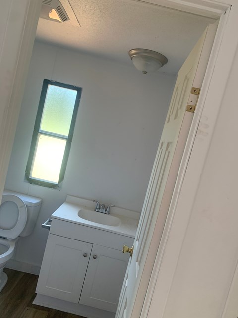 A white bathroom with a toilet, sink, and cabinet.