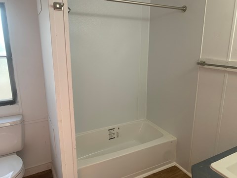 A white bathroom with a tub and toilet.