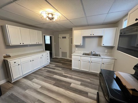 A kitchen with white cabinets and a black counter top.