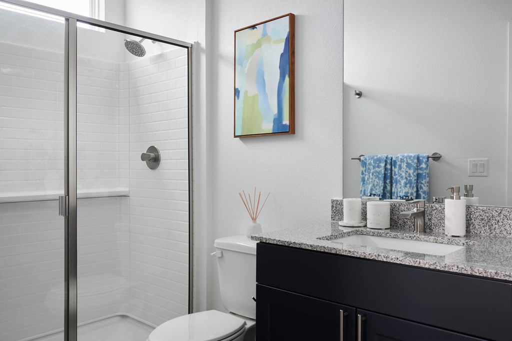 A bathroom with a toilet, sink, and a painting on the wall.