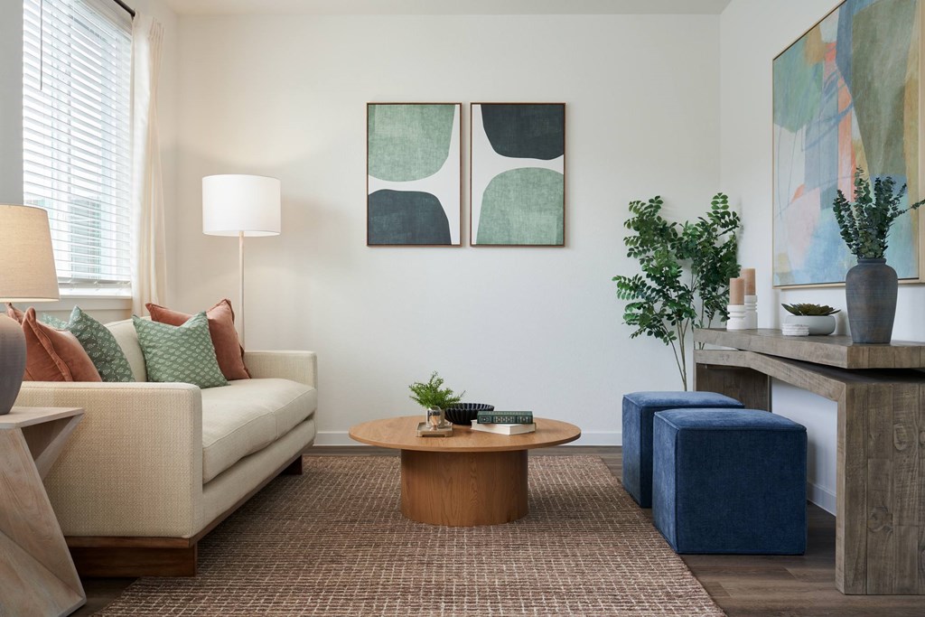 A living room with a white couch, a brown coffee table, and a blue ottoman.