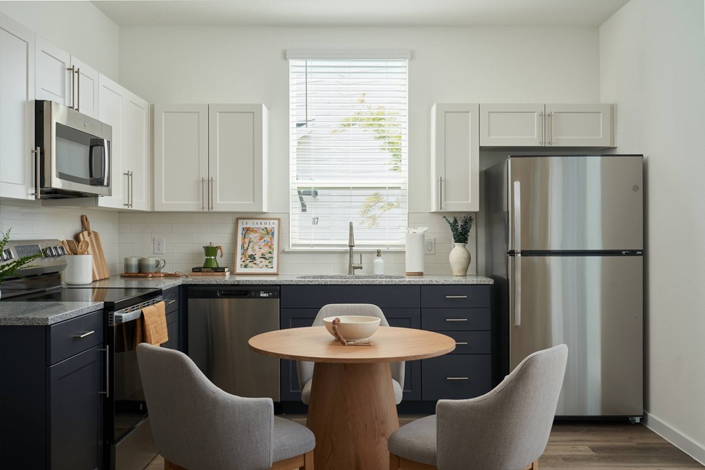 A kitchen with a table and chairs in front of a refrigerator.