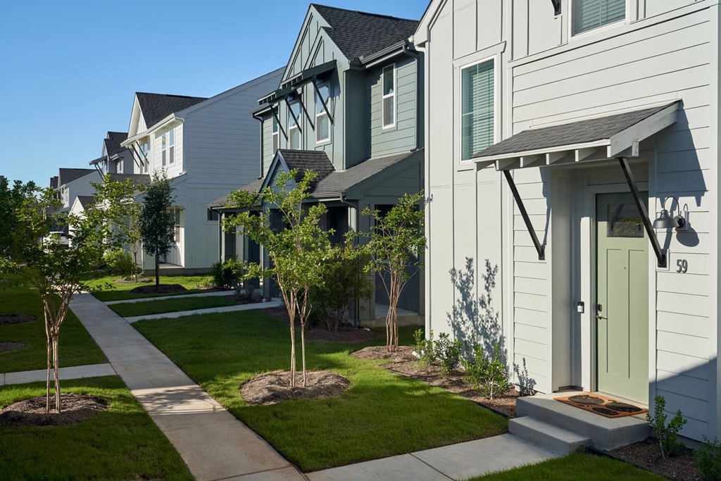 A row of houses with green doors and windows.