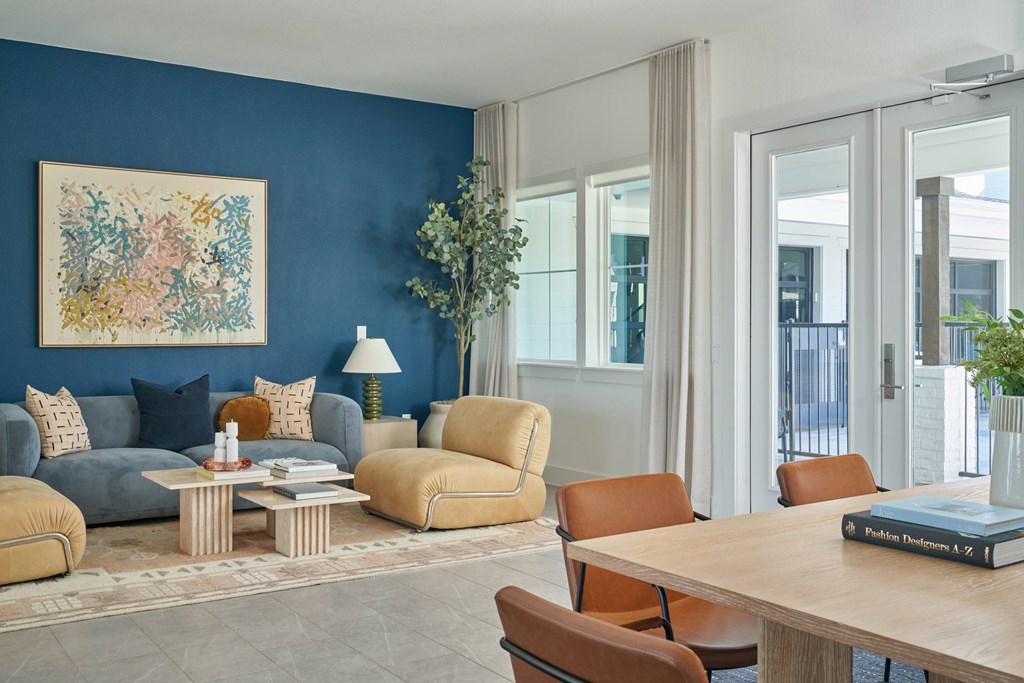 A living room with a blue wall and a painting on it.