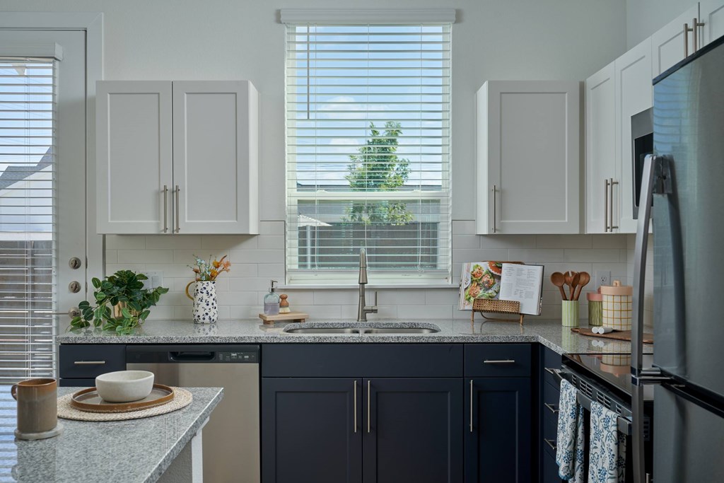 A kitchen with dark blue cabinets and a granite countertop.